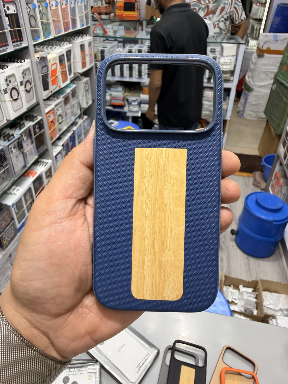 Wood panel textured MagSafe case in Navy Blue, held in hand