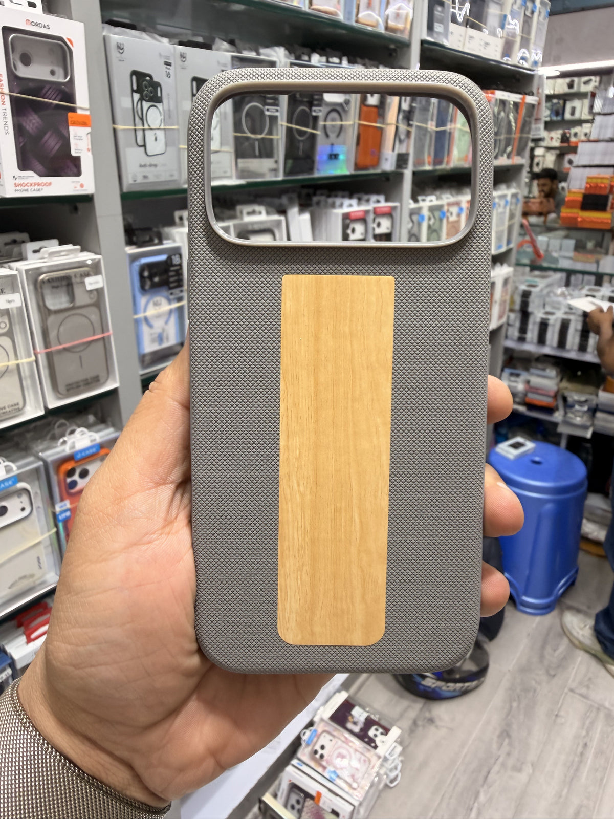 Wood panel textured MagSafe case in Grey, held in hand
